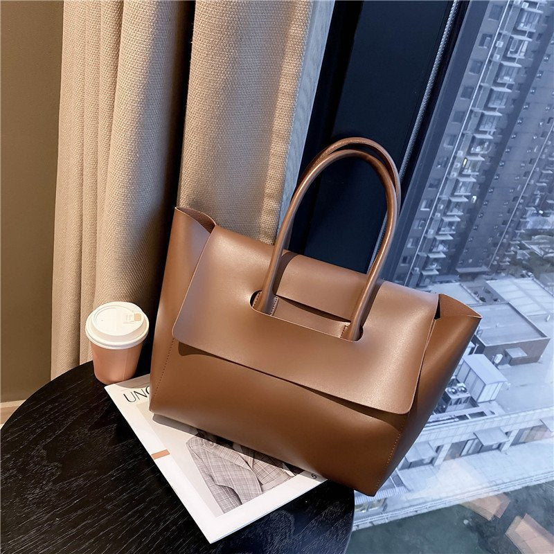 Brown leather handbag on a table with a cityscape view
