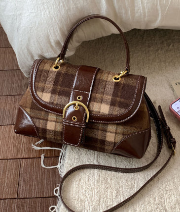 Brown plaid handbag with gold accents on a wooden floor.