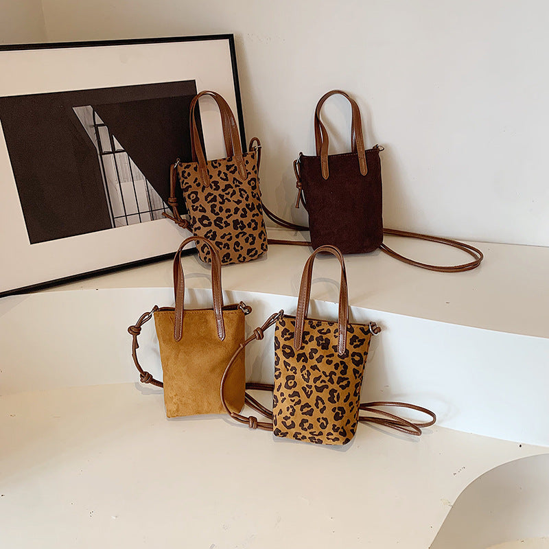Four handbags with leopard print and brown leather accents on a white surface.