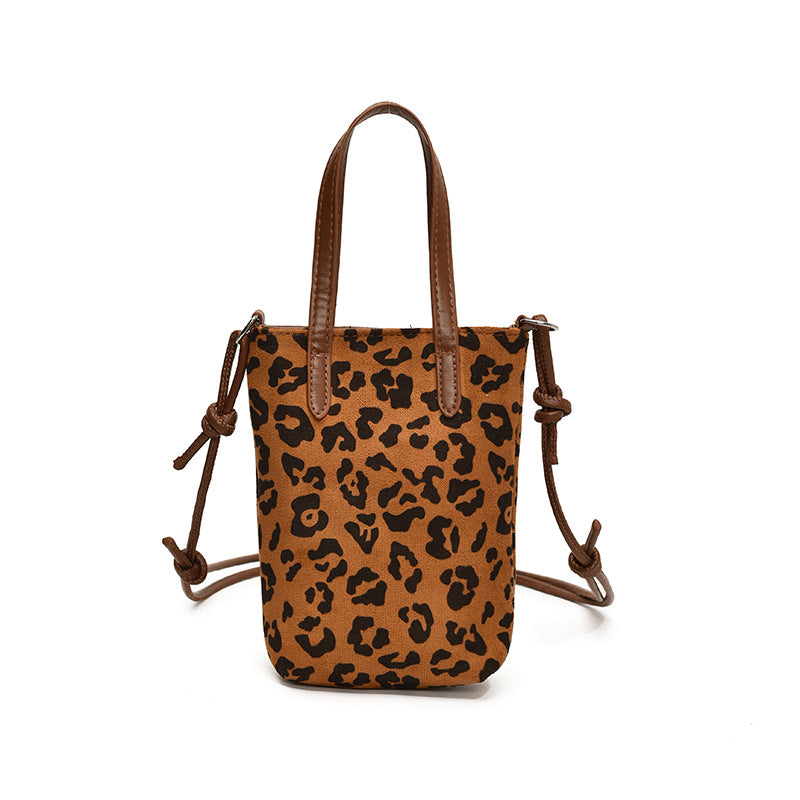 Leopard print handbag with brown leather straps on a white background