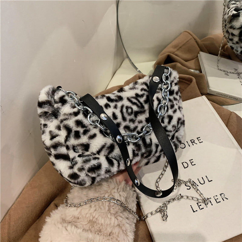 Leopard print handbag with chain details on a white surface