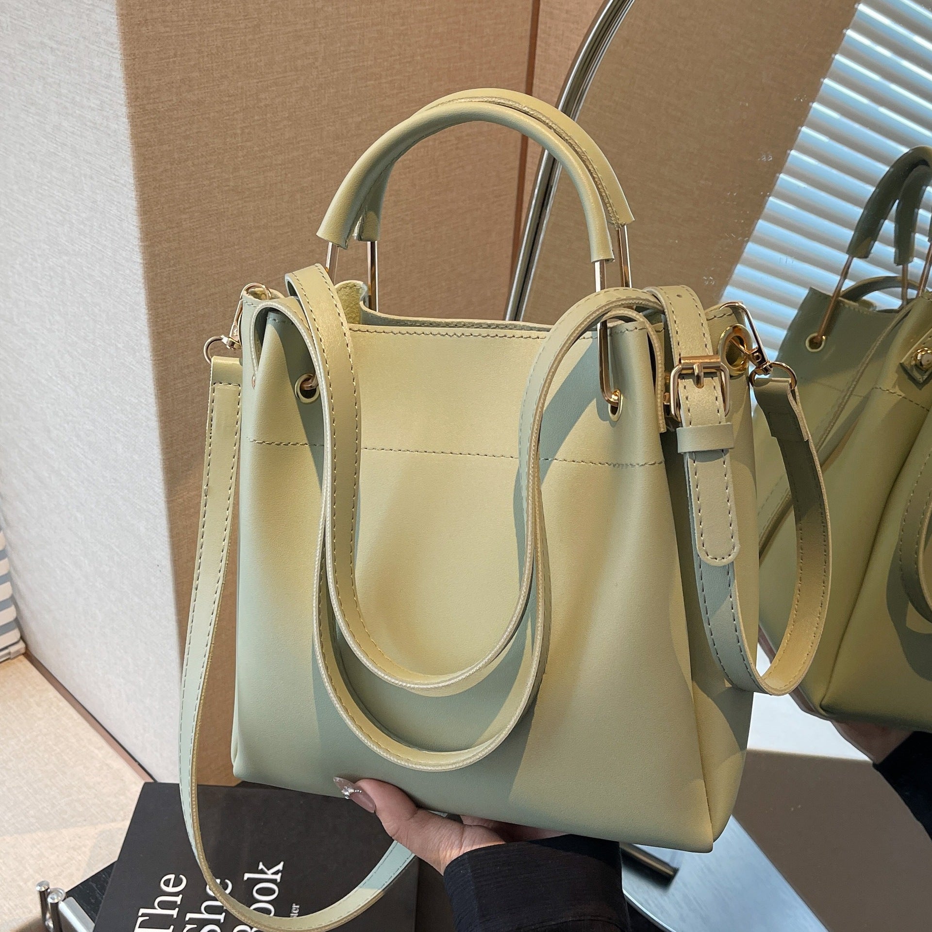 Light green handbag held by a person with a neutral background