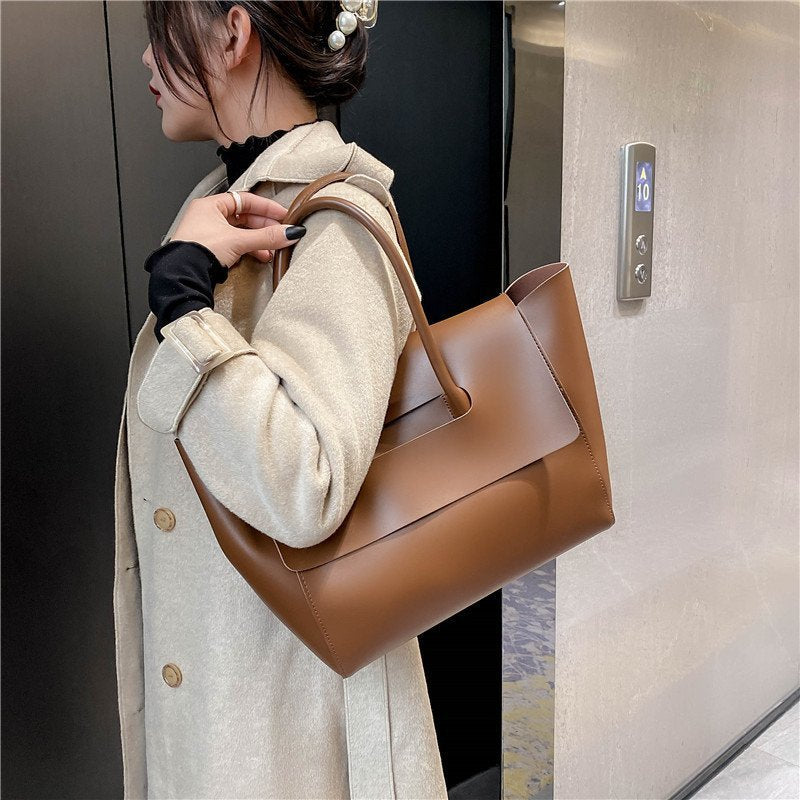 Person holding a brown leather handbag in an elevator