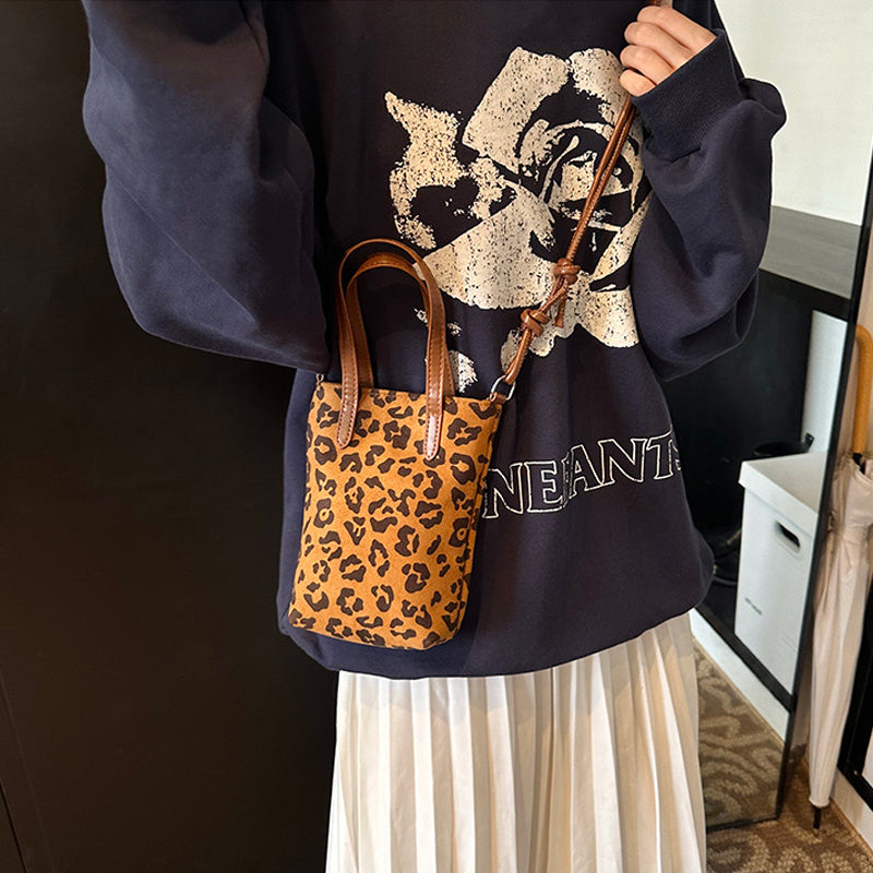 Person holding a leopard print handbag wearing a black sweatshirt with a floral design