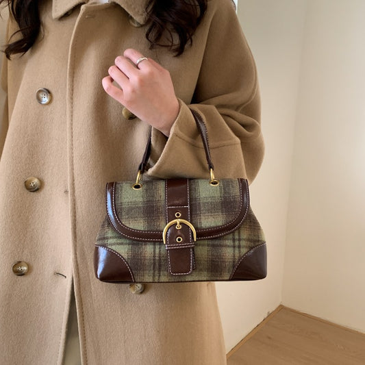 Person holding a plaid handbag with a beige coat