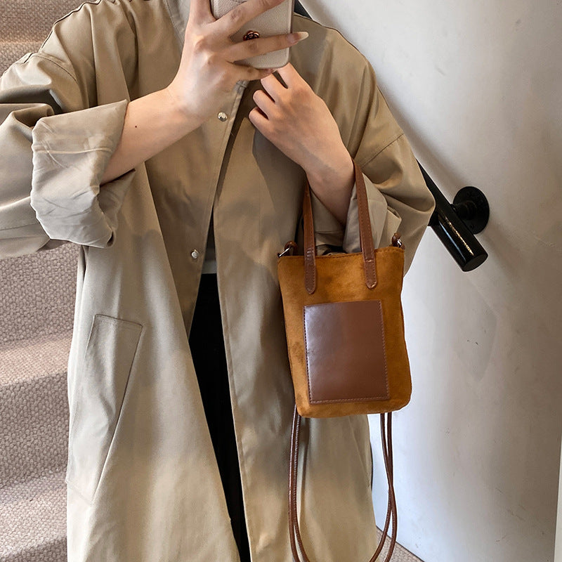 Person wearing a beige coat holding a brown leather handbag.