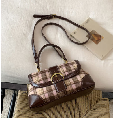 Plaid handbag with brown accents on a textured surface