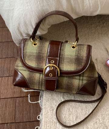 Plaid handbag with brown leather accents on a wooden floor.