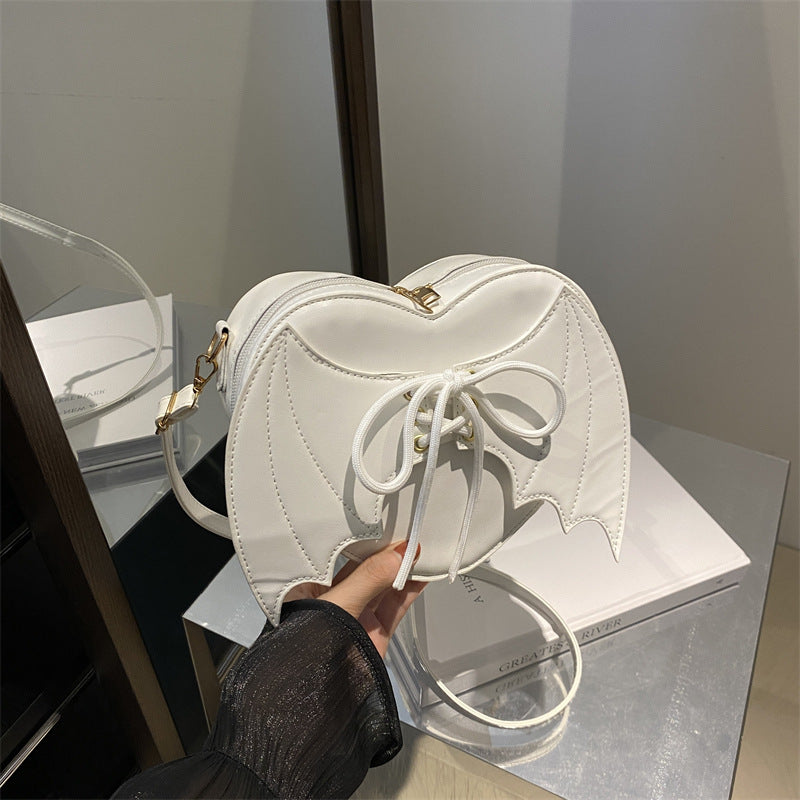 White heart-shaped bag held by a person with a blurred background