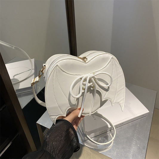 White heart-shaped bag held by a person with a blurred background