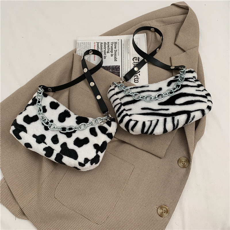 Two zebra print handbags with chain details on a beige jacket.